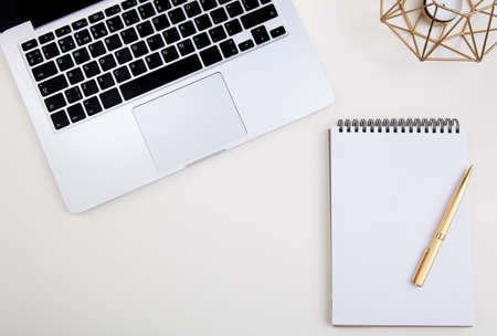 light office desk with laptop, white notebook mockup and golden penの写真素材