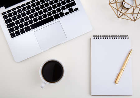 light office desk with laptop, white notebook mockup and coffee cup.の写真素材