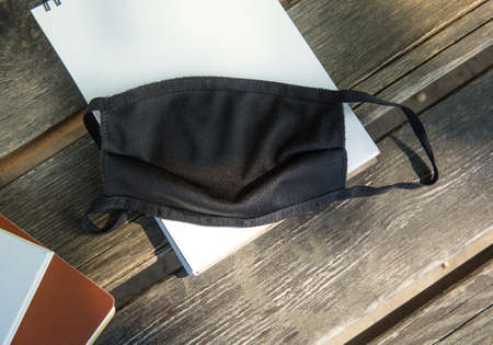 Black protective mask on notebooks on a park bench.の写真素材