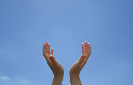 Closeup woman hands holding something on blue skyの写真素材