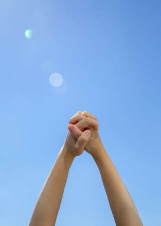 Closeup two young hands holding each other on the blue backgroundの写真素材