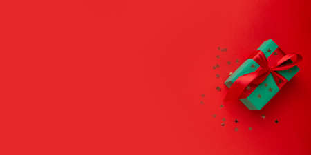 Christmas gift on red background with sequinsの写真素材