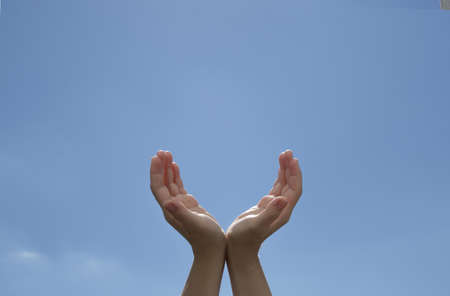 Woman hands with palms up on blue sky backgroundの写真素材