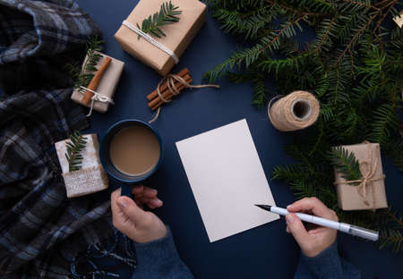 Hands hold a cup of coffee and a pen on a background of blue steel with giftsの写真素材