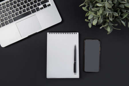 Black office desk with laptop, smartphone, notebook and pen. Top viewの写真素材