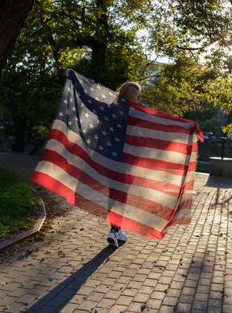 girl with glasses holding a fabric with a print of the American flagの写真素材