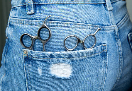 professional hairdressing scissors lie in the pocket of jeans.の写真素材