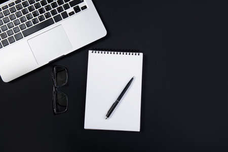 Black office desk with laptop, glasses and pen. Top viewの写真素材
