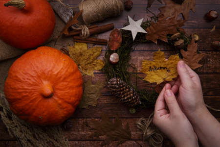 Childrens hands hold a yellow leaf and make an autumn wreathの写真素材