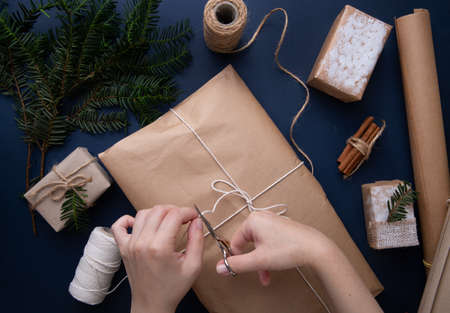 Hands wrapping a Christmas present on a blue tableの写真素材