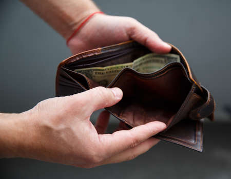 Male hands hold an open wallet and there is only one dollar in itの写真素材