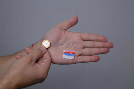 man hand holds euro coin and on the other palm course of 100 rubles is writtenの写真素材
