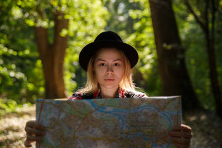 young caucasian woman in a hat looking at a geographic mapの写真素材