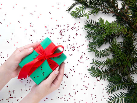 Hands hold Christmas gift with red ribbonの写真素材