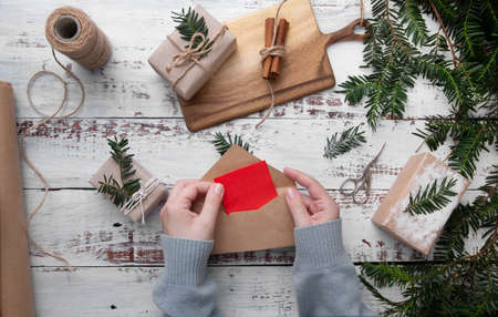 Girl hands hold an envelope with red paper on white backgroundの写真素材