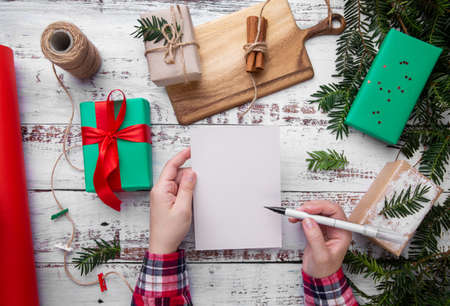 hands hold a pen and a postcard on the table next to giftsの写真素材