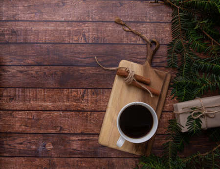 A cup of coffee stands on a cutting board on a wooden tableの写真素材