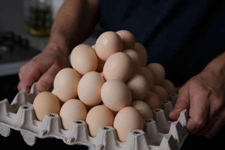 a man farmer holding a tray full of chicken eggs from the farmの写真素材