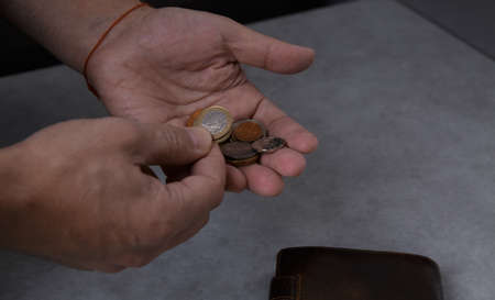 Hands of a man who counts metal coins on the palm on a light backgroundの写真素材