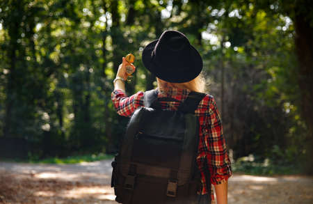 young caucasian woman in hat looks at the compass in her handの写真素材