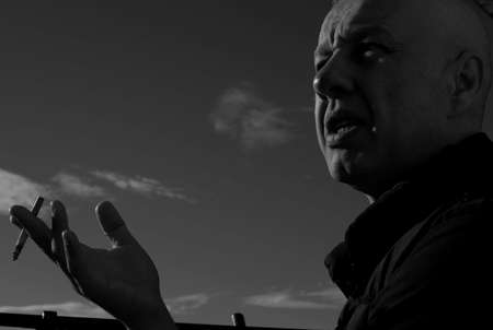 man smokes cigarette on background of the sky.black white photo.monochrome.の写真素材