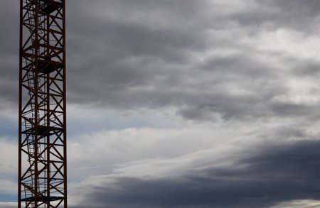 part of a construction crane against a blue sky with clouds, eveningの写真素材
