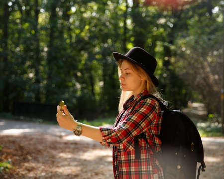 young caucasian woman in hat looks at the compass in her handの写真素材