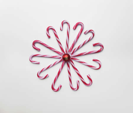 Caramel canes laid in the shape of a sun with a Christmas tree toyの写真素材