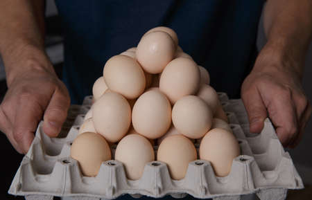 male hands holding a full tray of fresh and clean chicken eggsの写真素材