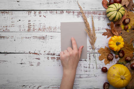 Woman hand holds grey card on wooden background .の写真素材