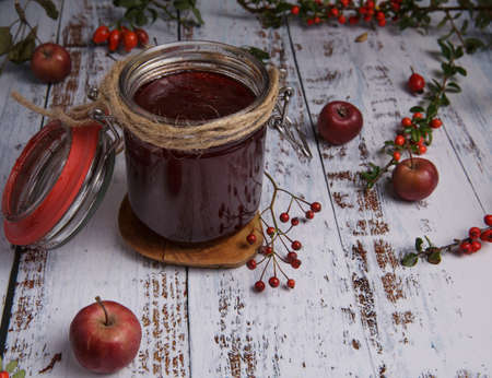jar of homemade strawberry jam in a glass jar stands on a white wooden table.の写真素材