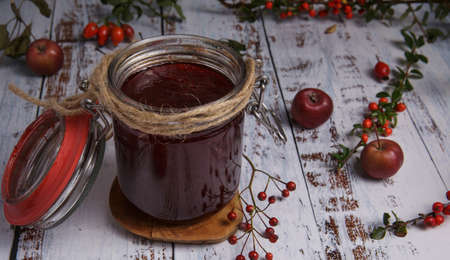 jar of homemade strawberry jam in a glass jar stands on a white wooden tableの写真素材