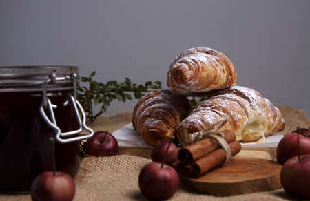 fresh croissants with cinnamon, strawberry jam and apples lie on the tableの写真素材
