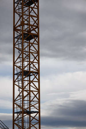 part of a construction crane against a blue sky with clouds, eveningの写真素材