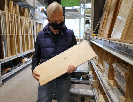 Man in black medical mask chooses a board in a building materials storeの写真素材