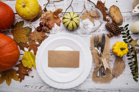 Autumn composition on an old wooden table with a plate and cutleryの写真素材