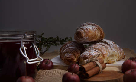 fresh croissants with cinnamon, strawberry jam and apples lie on the table.の写真素材