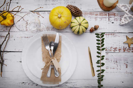 Autumn composition with a plate for cutlery, pumpkins and yellow leaves.の写真素材