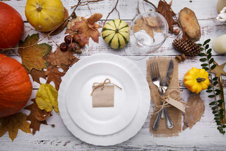 ripe pumpkin cutlery glass and yellow leaves on a wooden tableの写真素材