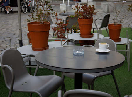 empty coffee cup and ashtray on a table in a secluded street cafe