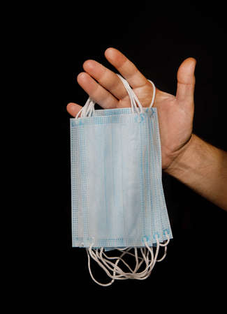 male hand holding several disposable medical masks.