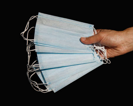 male hand holding several disposable medical masksの写真素材