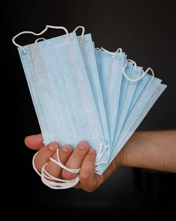 male hand holding several disposable medical masksの写真素材