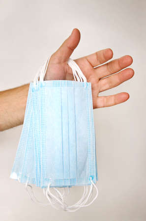 male hand holding several disposable medical masks.の写真素材