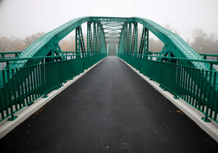 green bridge on an early foggy autumn morning on which no one walks.の写真素材