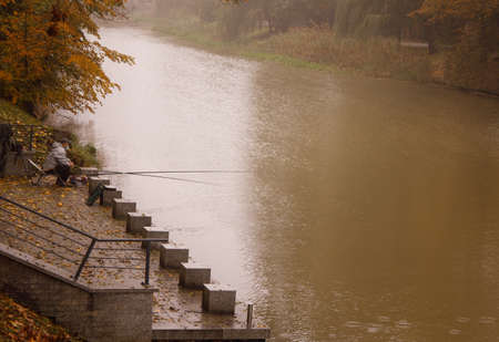 lone fisherman who catches fish on a foggy autumn morning on the riverの写真素材