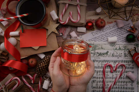children hands hold jar with garland on the background of a table with gifts