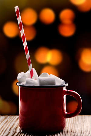 cup of cocoa with marshmallows stands on wooden table the background of garlands. High quality photoの写真素材