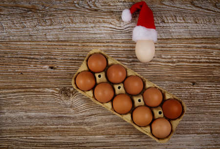 dozen eggs on wooden table, and one egg has Santa hat. selective focus.High quality photo.の写真素材