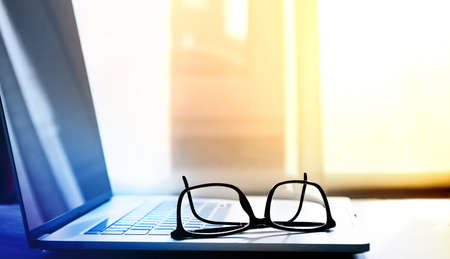 open laptop on which lie reading glasses in black frames. selective focusの写真素材